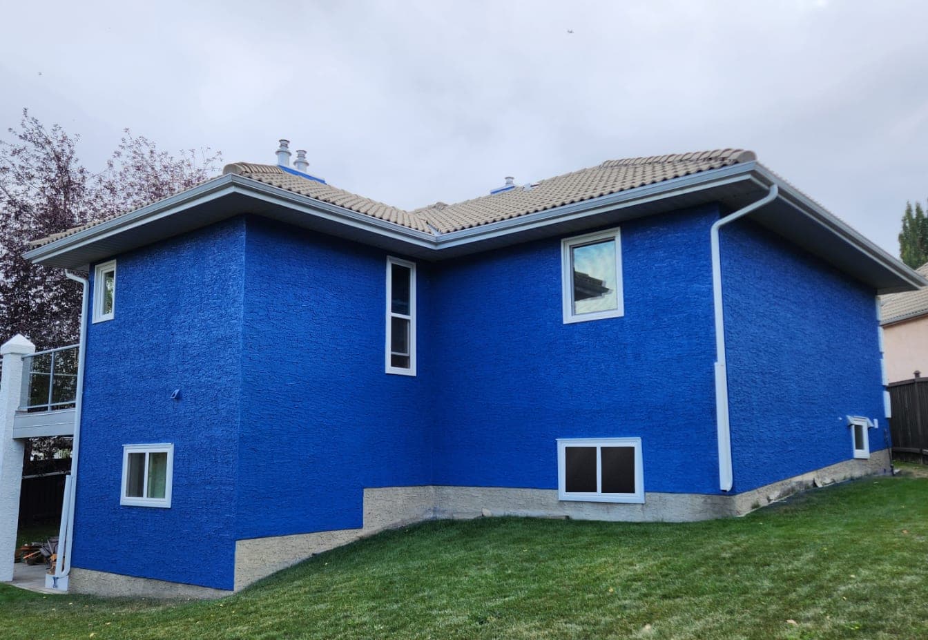 The same house after painting, stucco finished in a bold blue