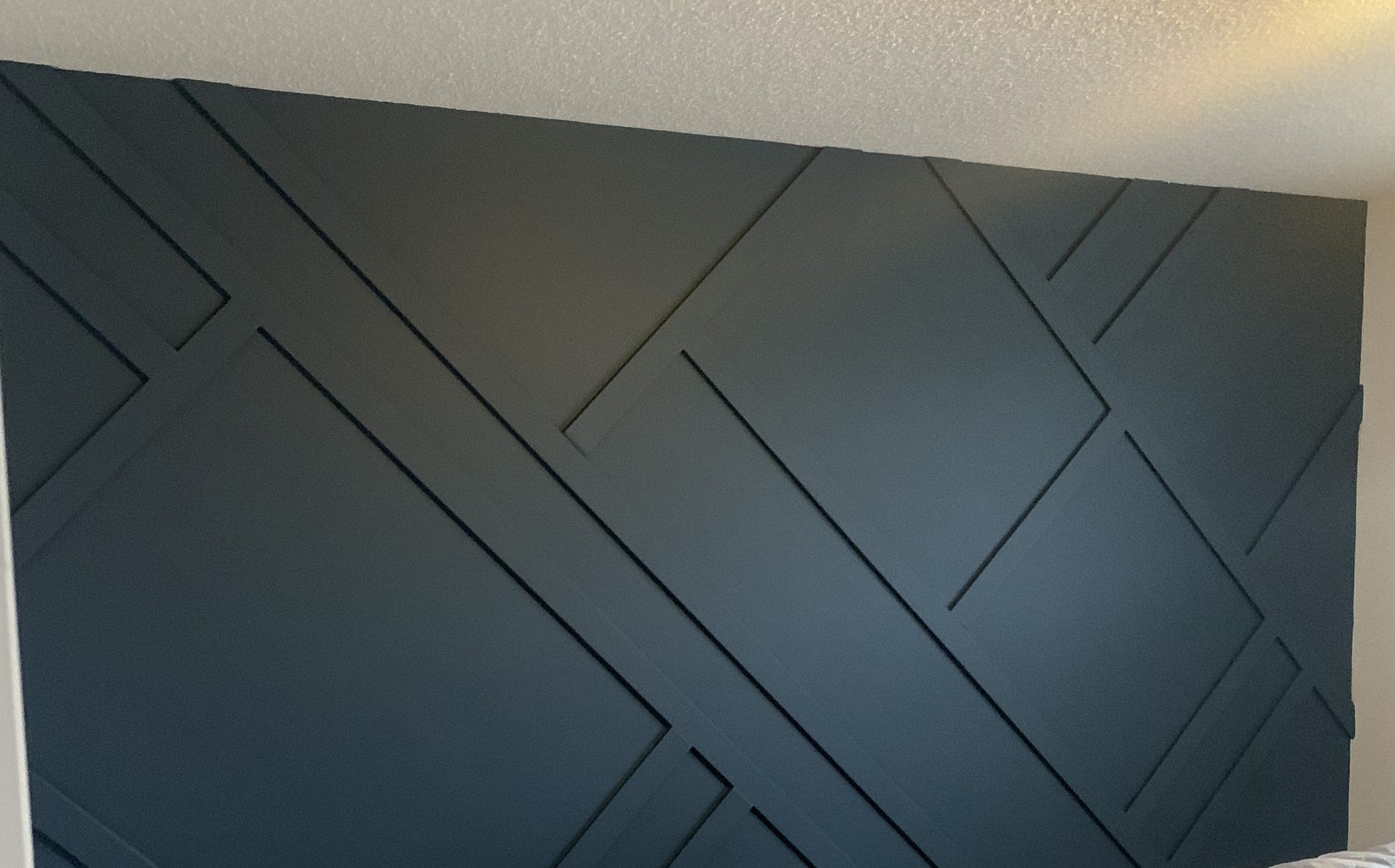 Bedroom feature wall finished in deep teal, with a diagonal batten pattern in raised trim